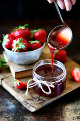 Selective focus. Strawberry jam in a jar. Fresh strawberries. Strawberry jam pours into a jar.
