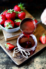 Selective focus. Strawberry jam in a jar. Fresh strawberries. Strawberry jam pours into a jar.