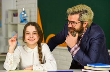 Schoolgirl studying. back to school. Little girl and man against blackboard. knowledge day concept. child with teacher in classroom at school. happy teachers day. teacher and schoolgirl on lesson