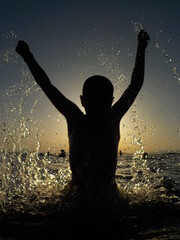 Silhouette of a child playing with the water in the sea 