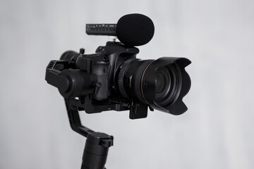 close up of modern dslr camera on 3-axis gimbal stabilizer with microphone over gray background