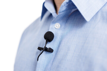 sound recording concept - close up of small lavalier clip-on microphone on male shirt