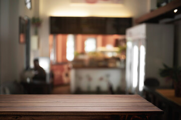 Empty wooden desk space and blurry background of cafe or Restaurant for product display montage.