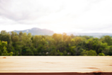 Empty wooden desk space and blurry background of mountain or hill.