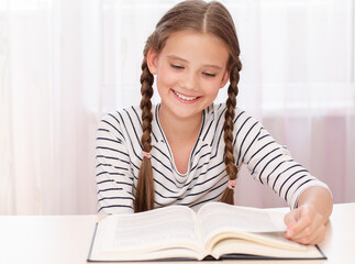 Education and school concept. Child is sitting at the desk and reading a book