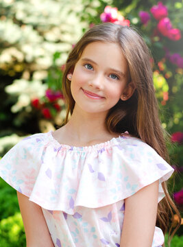 Portrait of adorable smiling little girl child in summer day. Happy preteen in the park