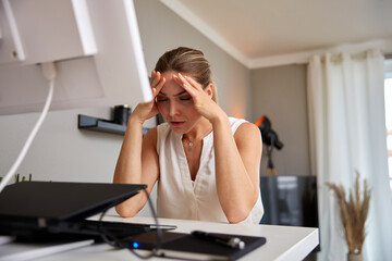 Businesswoman With Head In Hands Suffering From Headache