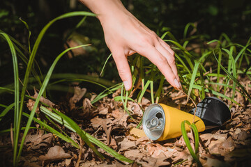 Environment concept, girl's hand reaches for a metal can of soda lying in the forest. concept and...