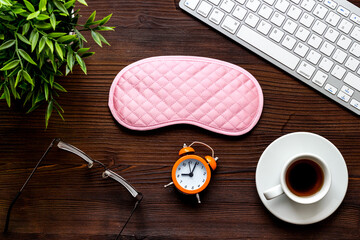 Flat lay of sleep mask on wooden office desk from above