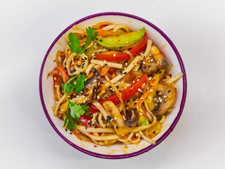 Udon noodles with meat in a plate on a white surface. With vegetables greens