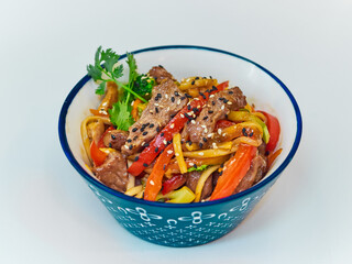 Udon noodles with meat in a plate on a white surface. With vegetables greens