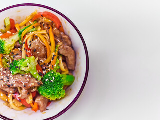 Udon noodles with meat in a plate on a white surface. With vegetables greens