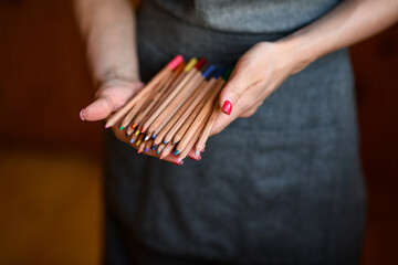 Close-up of many colored pencils in woman's hands.