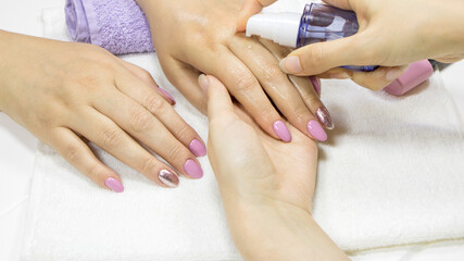The manicurist disinfects the client's hands. Manicure artist sterilize hand and nail for female in salon. Close-up Woman using hand sanitizer gel Cleaning hands with alcohol gel. Disinfectant Liquid.