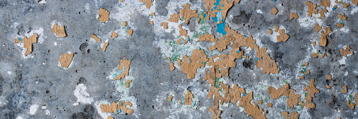 Peeling paint on the wall. Panorama of a concrete wall with old cracked flaking paint. Weathered rough painted surface with patterns of cracks and peeling. Wide panoramic texture for design background