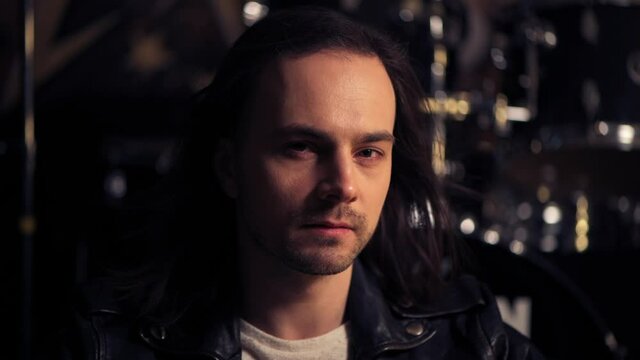 Brutal man with bristles on his face looking at the camera. Long dark hair