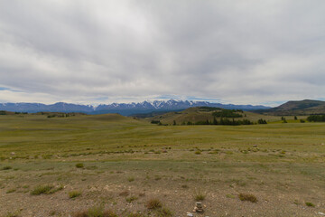 Panoramic view of a mountain valley summer, white clouds. Altai mountains. Dark day.