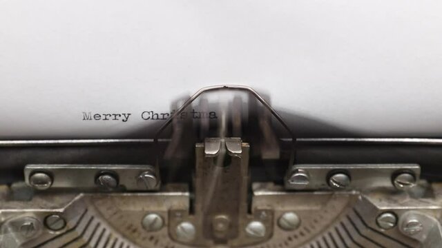 Typing a phrase Merry Christmas on a vintage typewriter close-up. concept of festive banner for national holiday
