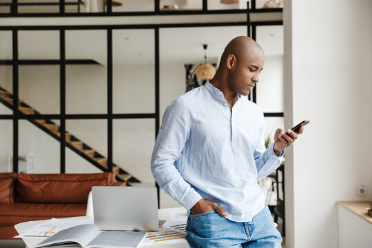 Photo of thinking african american man using mobile phone while working