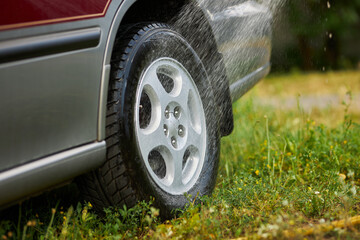 A man washes a car from a hose. Car wash.