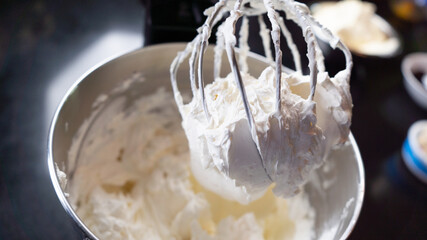 Whipped cream being prepared in dark kitchen. White cloudy cream - obrazy, fototapety, plakaty