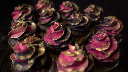 Glamorous black and pink cupcakes on dark background.