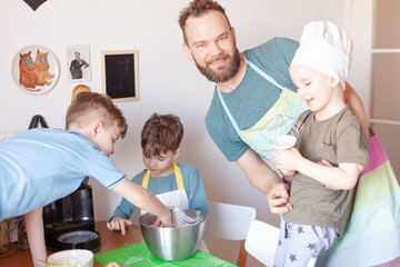 happy father with children cooks on paternity leave in the kitchen