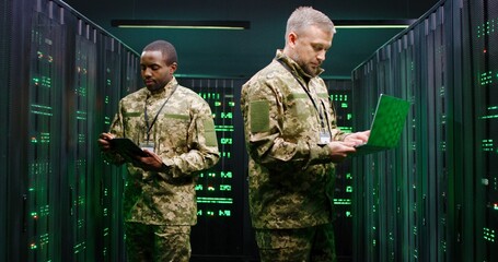 Multithnic military officials controlling servers and checking digital data in monitoring room....