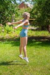 squat, jumping exercises. girl plays sports in garden. fitness after childbirth.