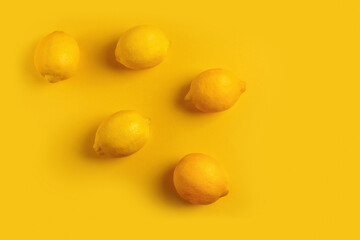 Five ripe lemons on a yellow background in the style of flat lay.