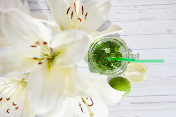 Fruit water and lily flowers. Refreshing summer drink with lime and mint. Concept of healthy and dietary nutrition.