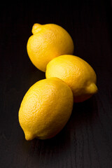 Fresh ripe lemons on black wooden background.