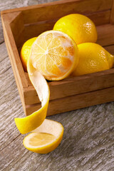 Wooden box with lemons on wooden table background. Half peeled lemon.