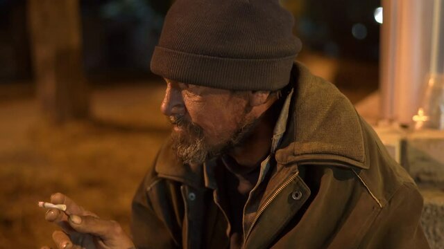 Face of lonely cold homeless man on the street at night.