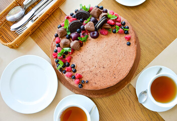 Chocolate cake in cocoa from above berries raspberries, black currant, biscuits, sweets on a round plate on the table. Cake slice, berries in macro. Birthday cake number 2. Top view, side view. 