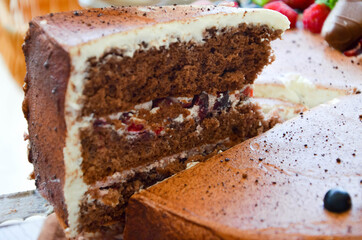 Chocolate cake in cocoa from above berries raspberries, black currant, biscuits, sweets on a round plate on the table. Cake slice, berries in macro. Birthday cake number 2. Top view, side view. 