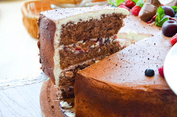Chocolate cake in cocoa from above berries raspberries, black currant, biscuits, sweets on a round plate on the table. Cake slice, berries in macro. Birthday cake number 2. Top view, side view. 