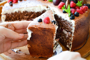 Chocolate cake in cocoa from above berries raspberries, black currant, biscuits, sweets on a round plate on the table. Cake slice, berries in macro. Birthday cake number 2. Top view, side view. 