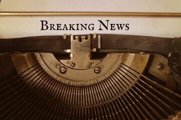 Breaking news is typed by an old typewriter on a paper.
