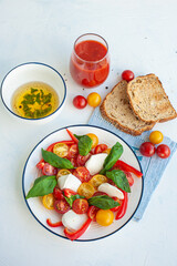 A light summer dinner. Red and yellow vegetable salad, tomato juice, basil sauce and toast. Vertical photo.