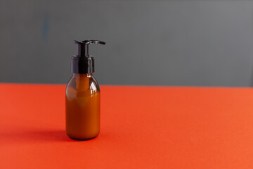 Clear plastic and glass brown bottles with organic cosmetics. Direct light. Beauty blogging minimalism concept. orange gray background
