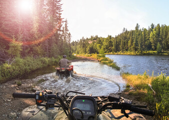 People driving ATV quads through water. Lake in Ontario, Canada. © Drepicter