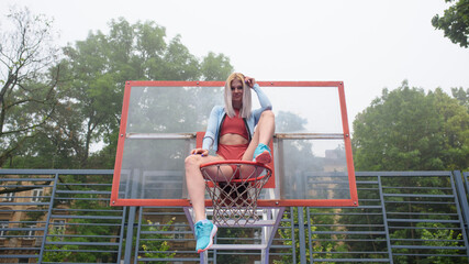
Young girl sitting on a basketball hoop