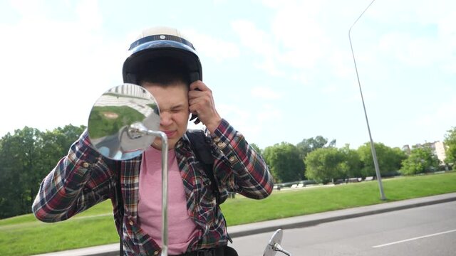 Young man with a motorcycle wears a helmet on his head. Close up slow motion footage