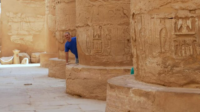 Happy Tourists Father and Son Look Out From Pillars or Columns and Waving Hands in Karnak Temple Complex In Luxor, Egypt. Family Concept of Traveling Worldwide