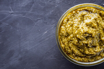 Delicious traditional italian pesto sauce on dark stone background