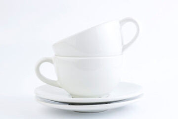 White cups and saucers stacked on a white background. Copy space