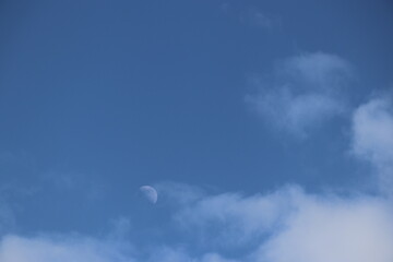 Blue sky and clouds with moon in background 