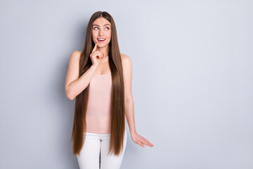Photo of charming perfect appearance model lady demonstrating ideal neat long hairstyle looking interested side empty space wear singlet trousers isolated grey color background