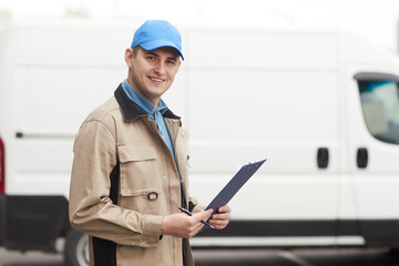 Portrait of young man smiling at camera while standing outdoors he working in delivery company